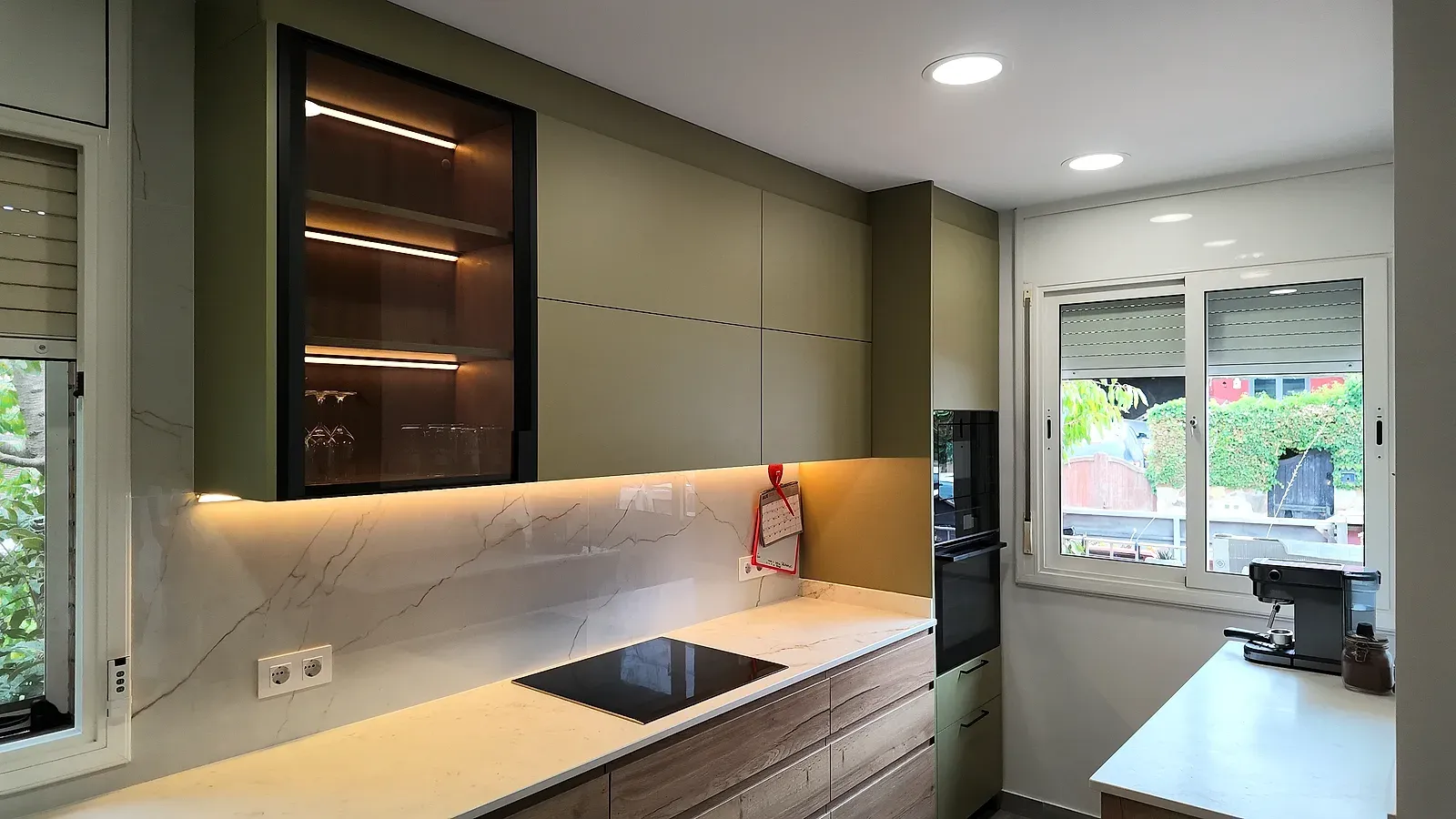 Cocina en Terrassa con encimera Neolith efecto mármol, muebles verde salvia y vitrina con LED