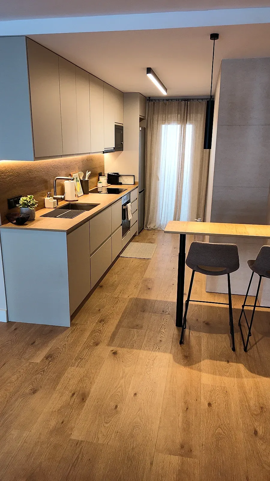 Cocina abierta al comedor con barra, tira LED y suelo de madera en toda la vivienda, Castelldefels